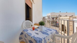 A balcony with a table, chairs, and a potted plant.