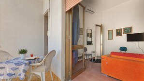A room with a dining table, chairs, a sofa, and a TV.