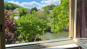 A view from a window overlooking a river, with trees and buildings in the background.