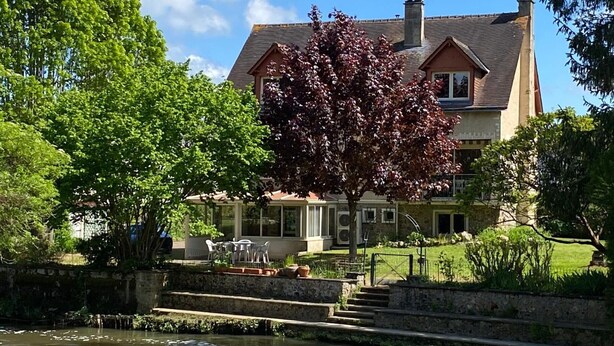 A large house with a garden and a pond in front.