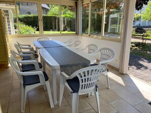 Relax in this serene sunroom with a garden view, featuring a spacious table and comfortable seating for six.