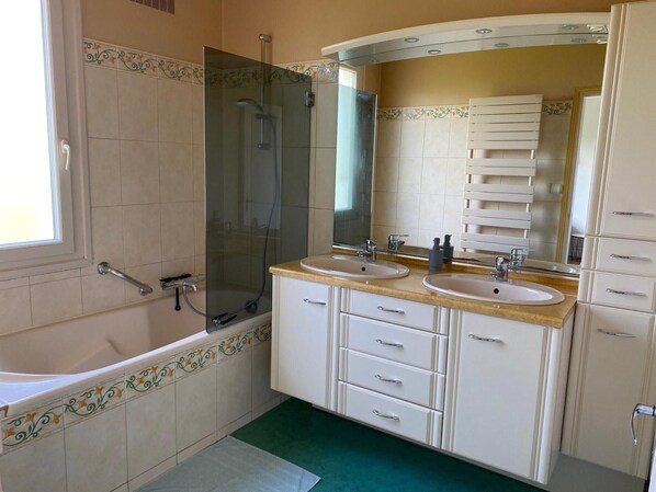 A bathroom with two sinks, a glass-enclosed shower, and a large mirror.