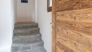 A wooden door with a metal handle, a stone staircase, and a framed picture on the wall. - Pilànous Residence - Junior Suite - Swiss Alps (Haute-Nendaz)