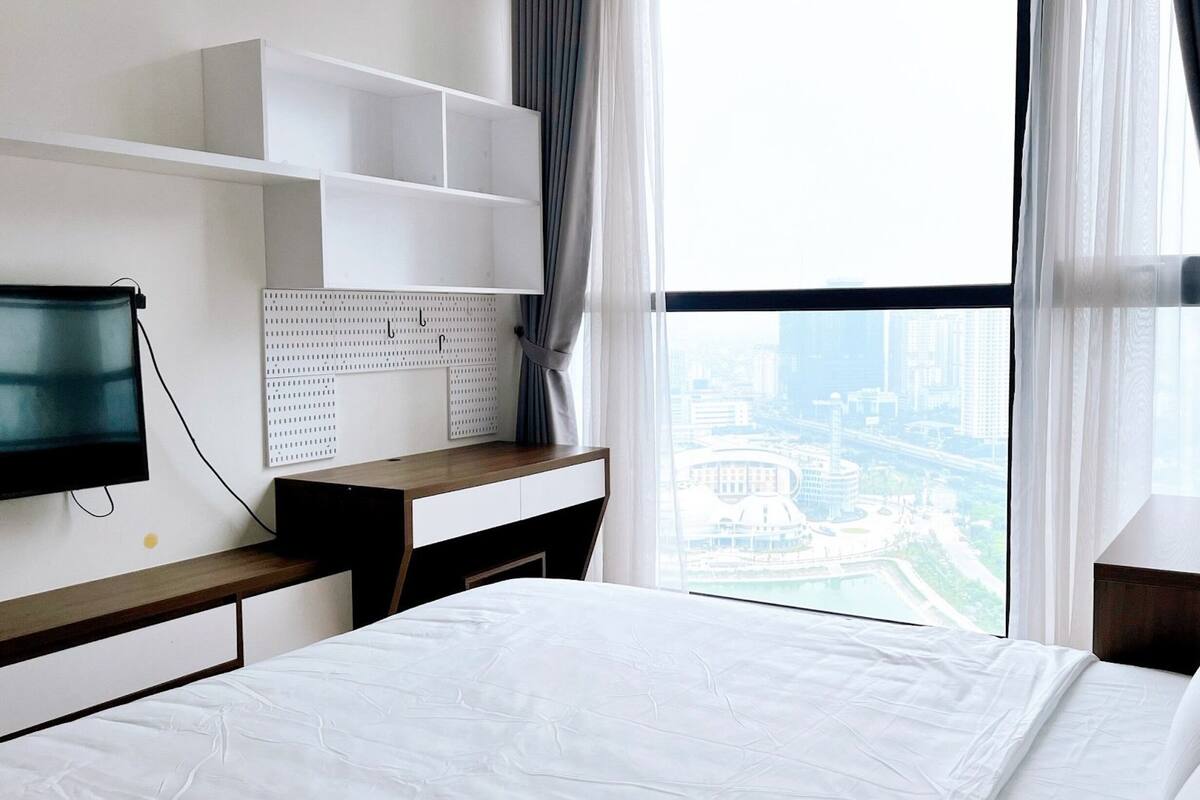 Ein Hotelzimmer mit Bett, Schreibtisch, Fernseher, Bilderleiste und Blick auf die Stadt.