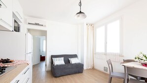 Una cocina moderna con un sofá gris, una mesa de comedor con sillas y una ventana con cortinas.