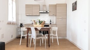 Una cocina moderna con armarios de madera, una mesa de comedor con sillas y una lámpara colgante.