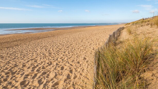 A wide sandy beach with gentle waves, a clear sky, and dunes with sparse vegetation. - Last Minute! 8-Person Holiday Home with WiFi Near Beach in La Tranche-sur-Mer (La Tranche-sur-Mer)
