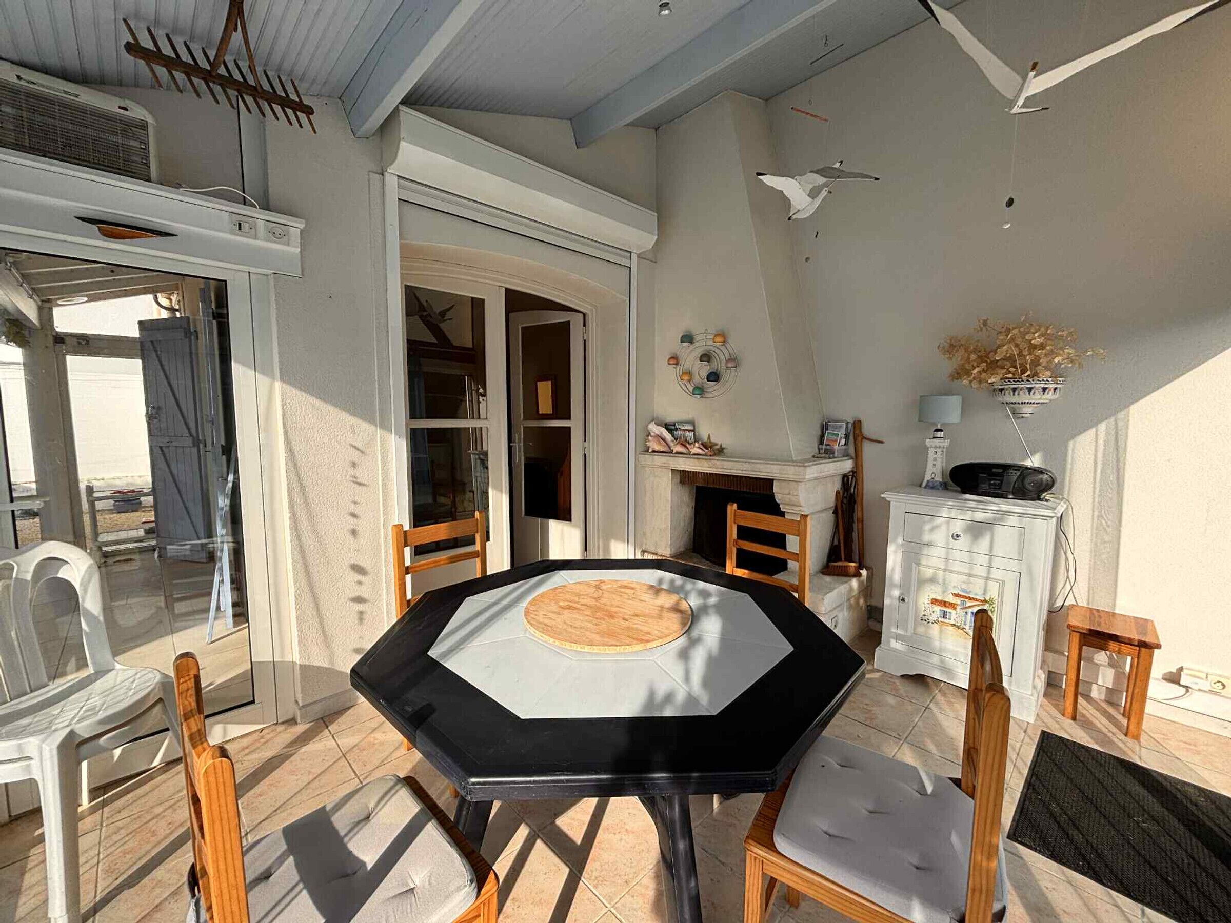 A dining area with a black table and wooden chairs, a white cabinet with a radio, and a fireplace.
