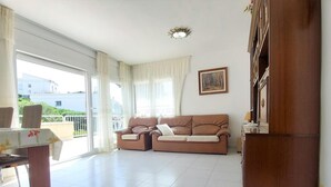 Amplia sala de estar con un conjunto de sofás, una mesa de comedor y vista al balcón.