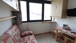 Une cuisine compacte avec une table en bois et un banc intégré, une fenêtre avec vue et un radiateur.