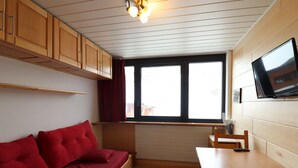 Une petite pièce comprenant un lit superposé en bois, une petite table et un téléviseur fixé au mur.