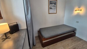 A small, cozy room with a single bed, a lamp, a speaker, and a framed picture on the wall. - Comfort studio 4 pax at the foot of slopes with balcony (Tignes)