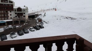 A snowy mountain scene with a ski lift, a parking area with cars, and a building with a sign that reads "La Gourmandise". - Comfort studio 4 pax at the foot of slopes with balcony (Tignes)