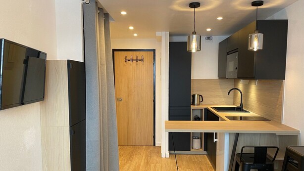 A modern kitchen with a built-in oven, a sink, and a dining area with stools. - Comfort studio 4 pax at the foot of slopes with balcony (Tignes)