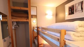 Ein Schlafraum mit Etagenbetten, einem Holzschrank und einem Spiegel.
