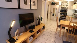 Ein Wohnzimmer mit Flachbildfernseher, einer Holzunterhaltungsecke und einem Essbereich mit Tisch und Stühlen.