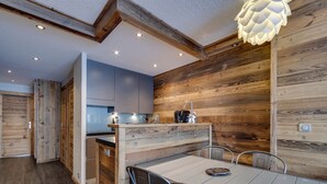 A modern kitchen with wooden accents, a dining area with metal chairs, and a ceiling light fixture. - Renovated apartment for 4, ski-in/ski-out, balcony, WIFI (Tignes)