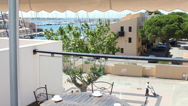A balcony with a view of a marina, a tree, and a building with a flat roof. - 6-person apartment with pool in Gruissan (Gruissan)