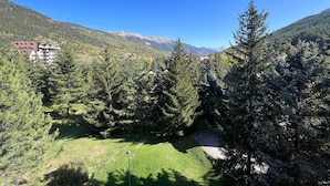 Paisaje montañoso con un edificio en primer plano y un cielo azul despejado.