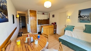 Una habitación acogedora con una mesa de comedor de madera, un sofá y una zona de cocina con armarios de madera y un lavamanos.