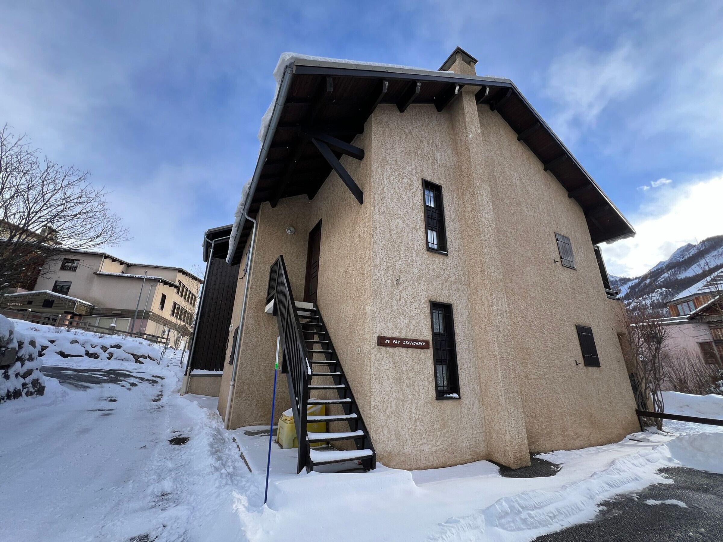 A building with a staircase leading to an entrance, a sign reading "HE PAS STATIONER," and snow on the ground.