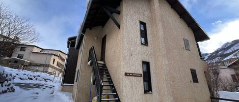 A building with a staircase leading to an entrance, a sign reading "HE PAS STATIONER," and snow on the ground.