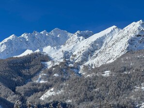 A mountain landscape with snow-covered peaks and a forested valley.