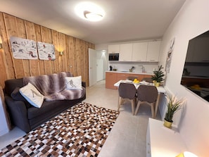 Un salon moderne avec un canapé, un tapis à motifs et un coin repas comprenant des chaises et une table.