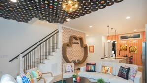 A modern living room with a staircase, a sofa set, and a ceiling decorated with vinyl records. - Hot Tub & Rooftop Views - Twang Town Terrace (Nashville)