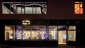 Un edificio moderno con un letrero que dice 'City Hub', ventanas amplias y un diseño geométrico de neón.