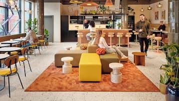 A modern lounge area with seating, a bar, and a kitchen area.