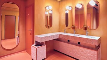 A modern bathroom with a vanity, two sinks, and three mirrors with lights.