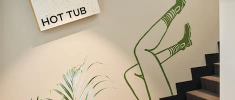 Una scala con un cartello a parete che indica “HOT TUB” e un disegno astratto verde.