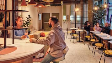 Een modern interieur met ronde tafels, hanglampen en een gevarieerde zithoekindeling.