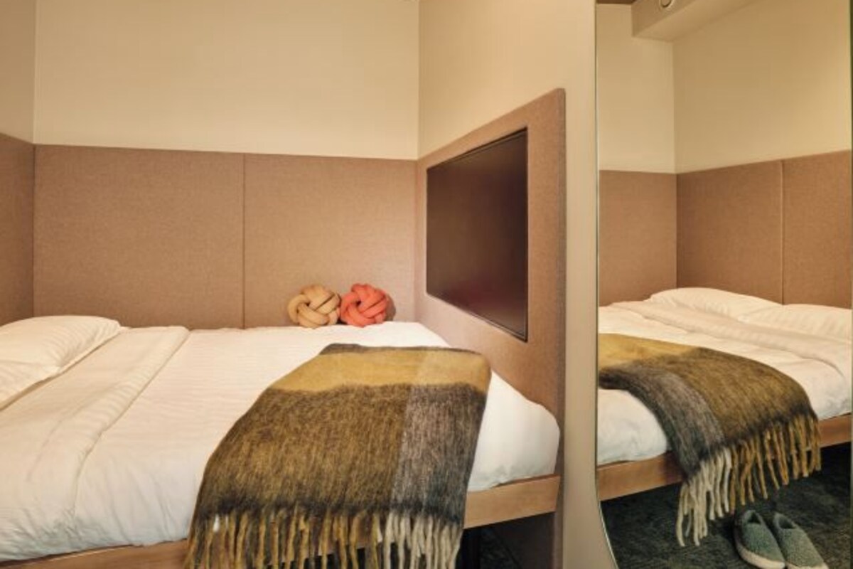 A hotel room with two beds, a large mirror, and a wooden headboard.