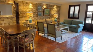 Un salón acogedor con una pared de piedra, una mesa de comedor con sillas, un sofá y un sillón verde.