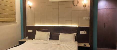 A hotel room with a bed, nightstands, an air conditioner, and a wardrobe.