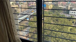 Vista de un paisaje urbano a través de una ventana, que muestra edificios, una carretera y algo de vegetación.