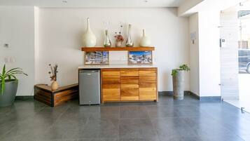 A reception area with a wooden cabinet, a small refrigerator, and a potted plant.