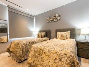 A bedroom with two beds, a bedside table, a lamp, and a wall-mounted decoration.