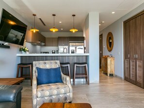 A modern kitchen with a central island, bar stools, and pendant lighting.