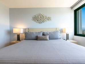 A neatly made bed with a quilted cover, two bedside lamps, and a decorative wall piece above the bed.