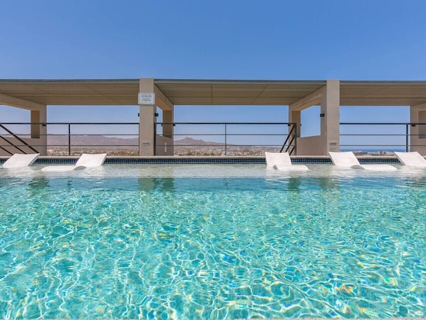 A swimming pool with clear water, surrounded by a covered area with steps leading down to the water.