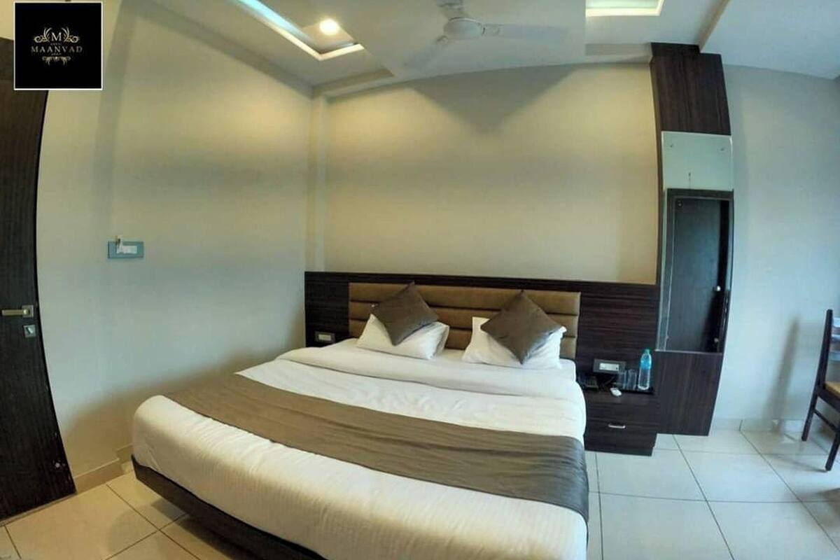 A modern hotel room with a large bed, a built-in wardrobe, a mirror, and a ceiling fan.