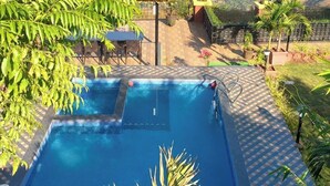 A pool area with a view of a mountainous landscape. - Blossom Stay (Mahabaleshwar)