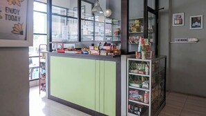 A modern interior with a counter displaying snacks and a refrigerated display case. - Take Guesthouse 1 (Jambi)