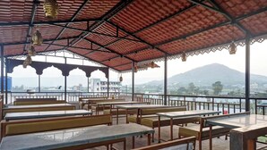 Un espacio de estar al aire libre con mesas y bancos, con vistas a un paisaje montañoso.