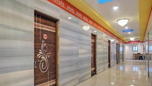 Un pasillo de hotel con paredes de mármol, puertas de madera con paneles decorativos y un piso limpio y pulido.
