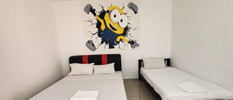 A hotel room with a large bed, a smaller bed, and a wall decoration of a cartoon character.