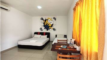 Two single beds with white bedding and a black headboard, a small table with a chair and personal items, and a large cartoon character mural adorn this cozy space.